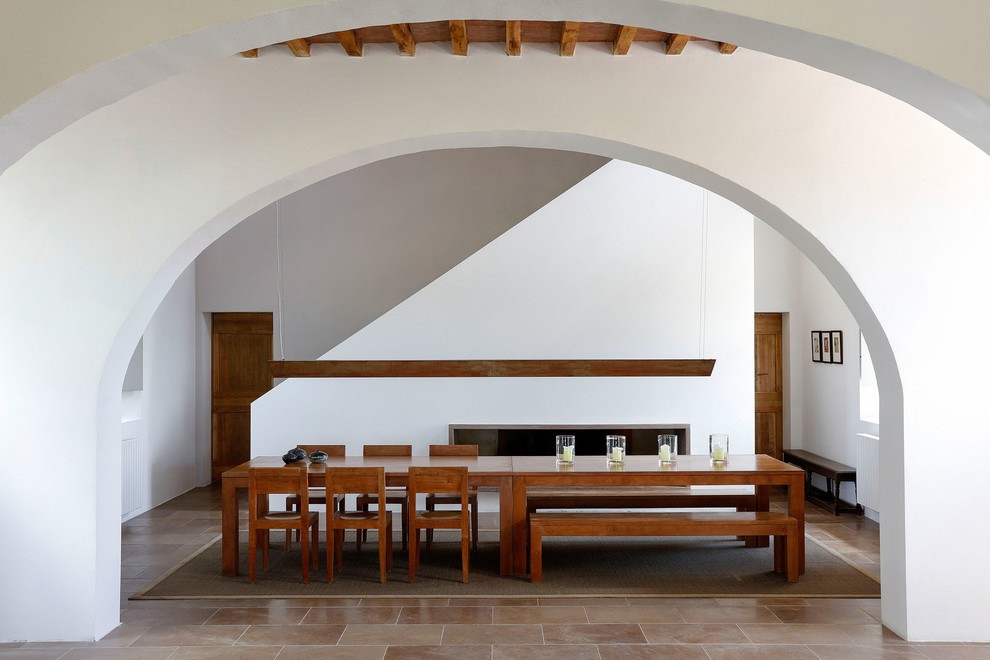 Modelo de comedor mediterráneo con paredes blancas, chimenea lineal y suelo marrón