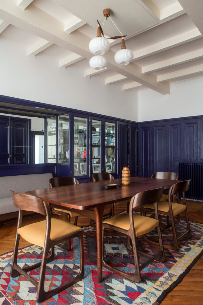 Geschlossenes, Großes Eklektisches Esszimmer mit blauer Wandfarbe, braunem Holzboden, braunem Boden und vertäfelten Wänden in Paris