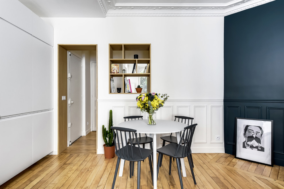 Design ideas for a scandi enclosed dining room in Paris with white walls, medium hardwood flooring and beige floors.