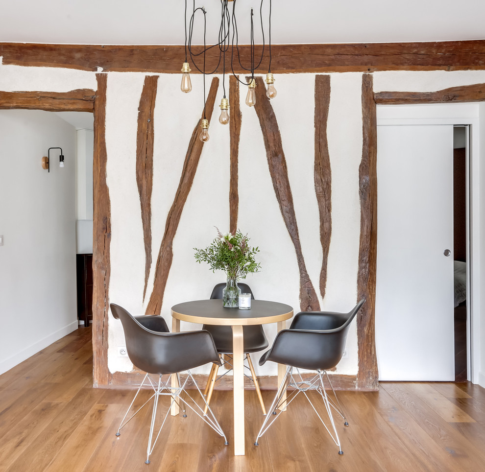 Cette photo montre une salle à manger ouverte sur le salon tendance avec un mur blanc, un sol en bois brun et un sol marron.