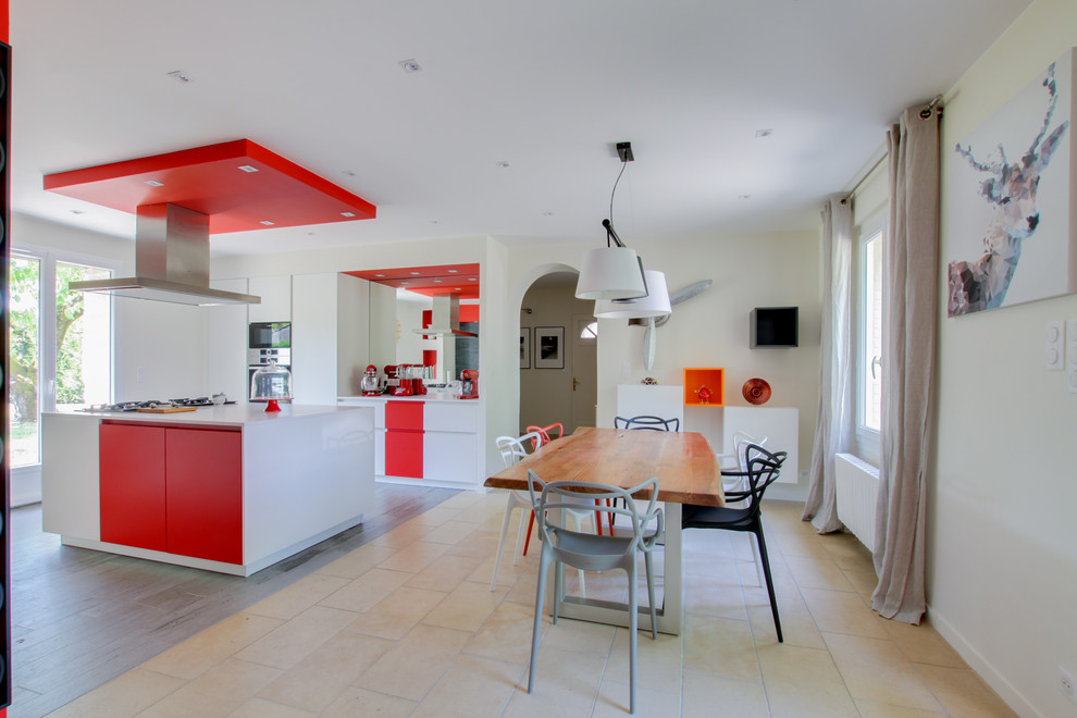 Aménagement d'une grande salle à manger ouverte sur la cuisine contemporaine avec un mur rouge, aucune cheminée et un sol beige.