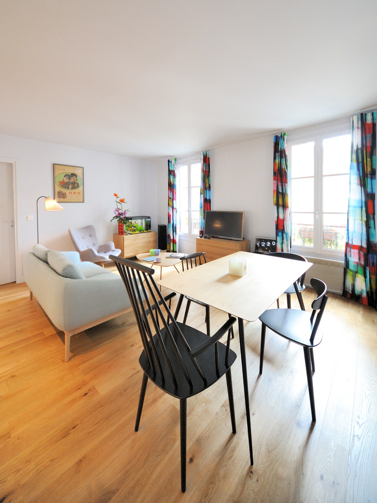 Aménagement d'une salle à manger ouverte sur le salon contemporaine avec un mur blanc, un sol en bois brun et aucune cheminée.