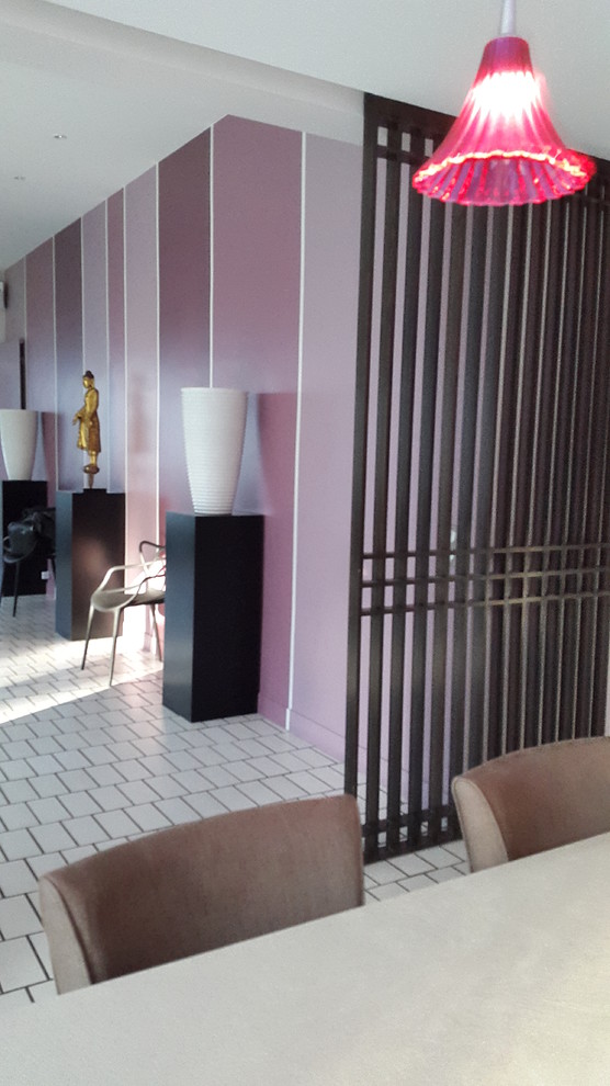 Immagine di un'ampia sala da pranzo minimal con pareti multicolore, pavimento con piastrelle in ceramica, camino bifacciale e cornice del camino in intonaco