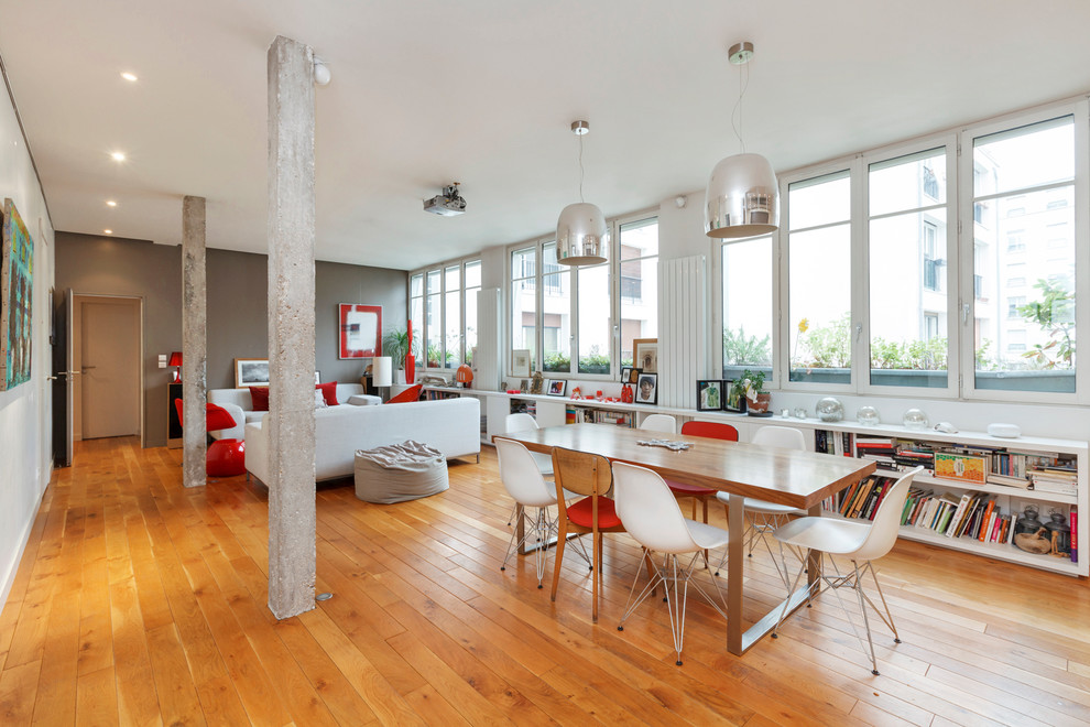 Foto di una grande sala da pranzo aperta verso il soggiorno minimal con pareti multicolore, pavimento in legno massello medio e nessun camino