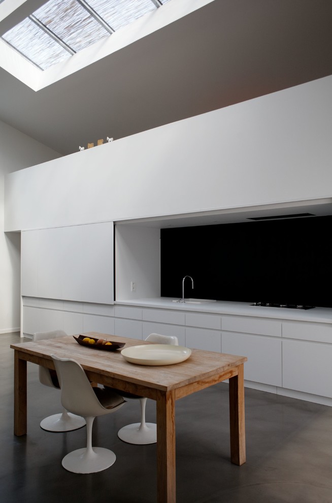 Inredning av ett modernt mellanstort kök med matplats, med vita väggar och betonggolv