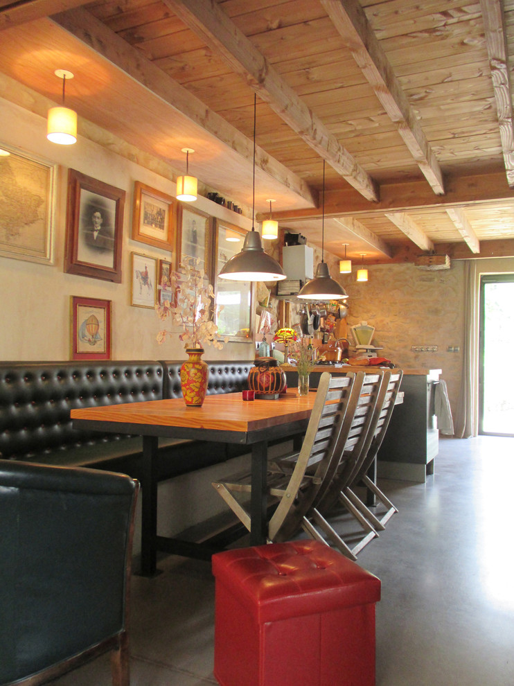 Immagine di una grande sala da pranzo aperta verso il soggiorno country con pareti beige e pavimento in cemento