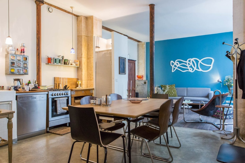 Cette photo montre une salle à manger ouverte sur le salon tendance de taille moyenne avec un mur bleu, sol en béton ciré et un sol gris.