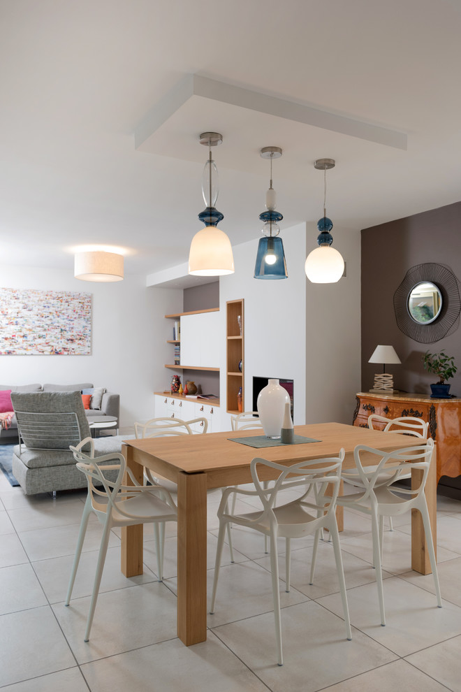 Réalisation d'une salle à manger ouverte sur le salon design avec un mur gris et un sol beige.