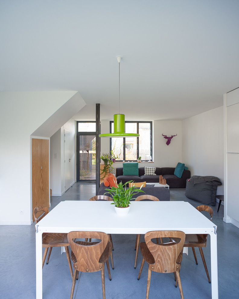 Foto di una sala da pranzo aperta verso il soggiorno design di medie dimensioni con pareti bianche, pavimento in cemento e nessun camino