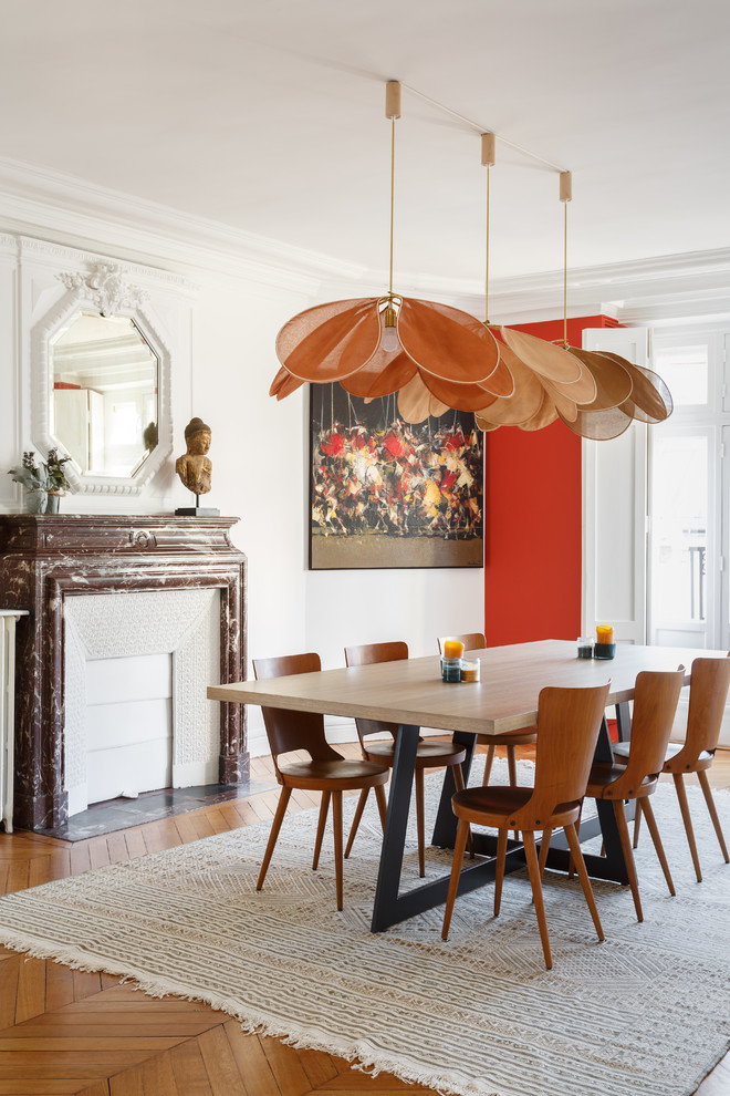 Ispirazione per una sala da pranzo moderna chiusa con pareti bianche, pavimento in legno massello medio, camino classico e pavimento marrone