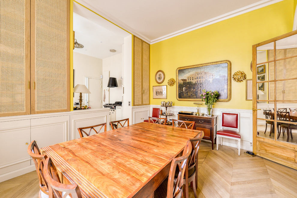Foto di una sala da pranzo aperta verso il soggiorno minimal di medie dimensioni con pareti gialle, parquet chiaro e nessun camino