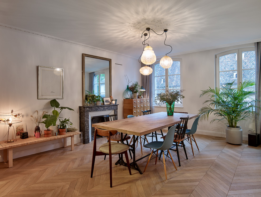 Example of a danish medium tone wood floor and brown floor dining room design in Strasbourg with white walls and a standard fireplace