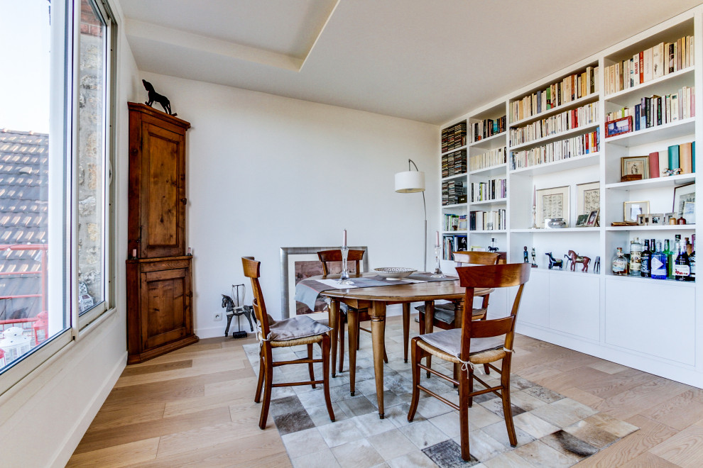 Cette image montre une grande salle à manger ouverte sur le salon design avec un mur blanc, parquet clair, une cheminée d'angle, un manteau de cheminée en pierre et un sol beige.