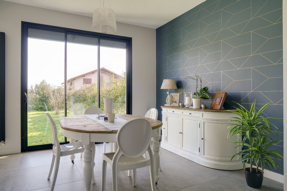 Cette image montre une grande salle à manger ouverte sur le salon design avec un mur bleu, un sol en carrelage de céramique, aucune cheminée et un sol gris.