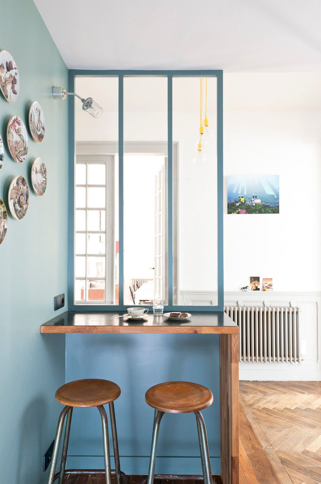 Immagine di una piccola sala da pranzo aperta verso il soggiorno contemporanea con pareti blu, pavimento in legno massello medio e nessun camino