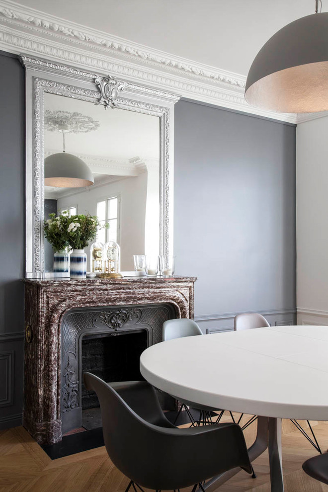 Источник вдохновения для домашнего уюта: столовая в стиле неоклассика (современная классика) с серыми стенами, паркетным полом среднего тона, стандартным камином и коричневым полом