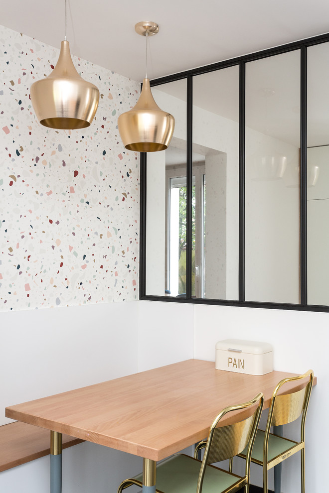 Cette photo montre une salle à manger ouverte sur la cuisine tendance avec un mur blanc.