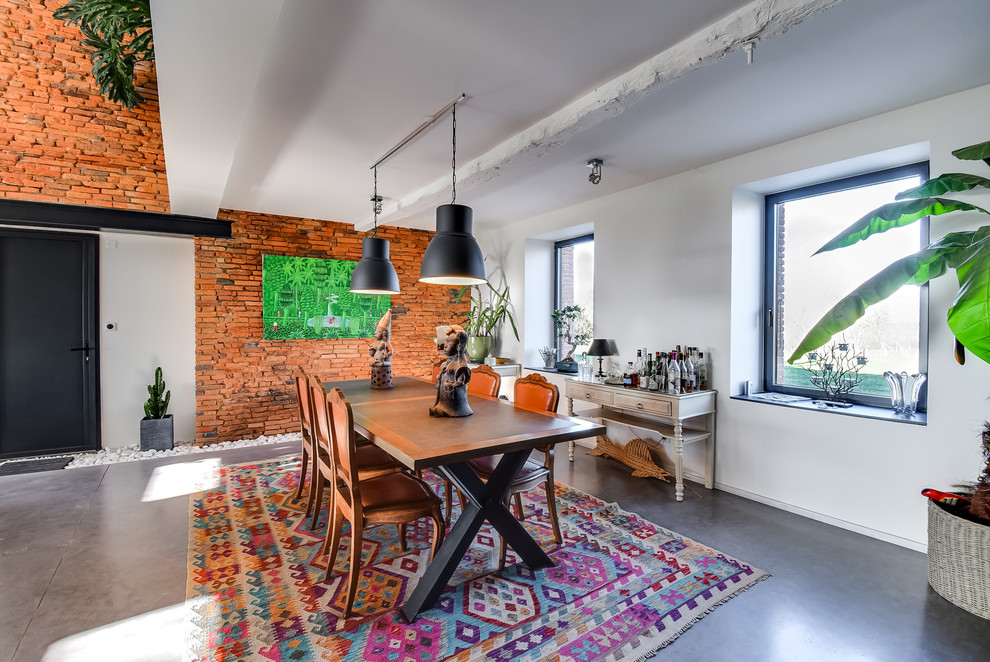 Foto di un'ampia sala da pranzo aperta verso la cucina bohémian con pareti rosse, pavimento in cemento e pavimento grigio