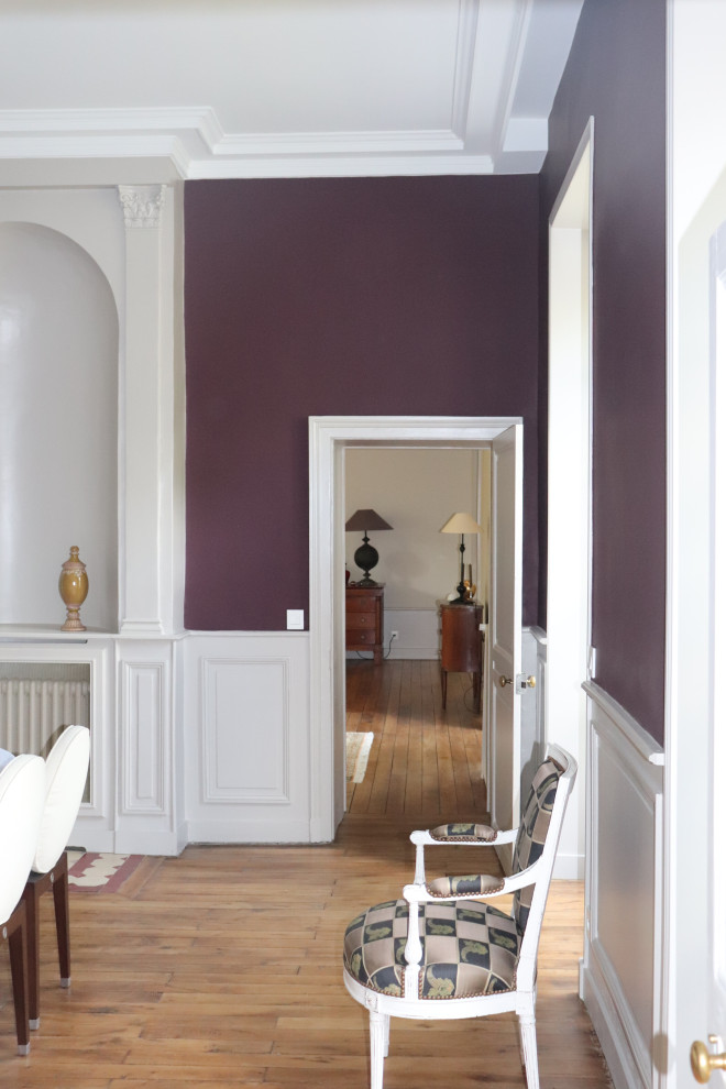 This is an example of a medium sized classic dining room in Clermont-Ferrand with purple walls, light hardwood flooring, brown floors and wainscoting.