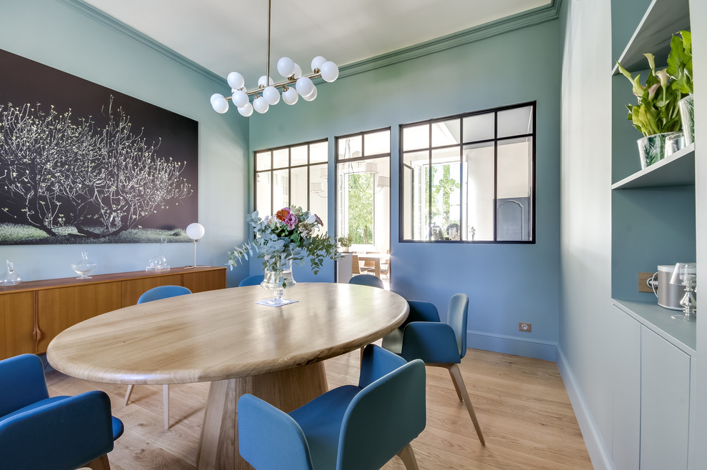 Idée de décoration pour une salle à manger design avec un mur bleu, parquet clair et un sol beige.