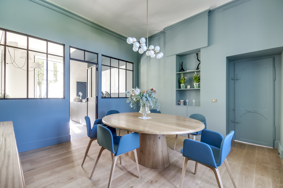 Foto de comedor actual cerrado con paredes azules, suelo de madera clara y suelo beige