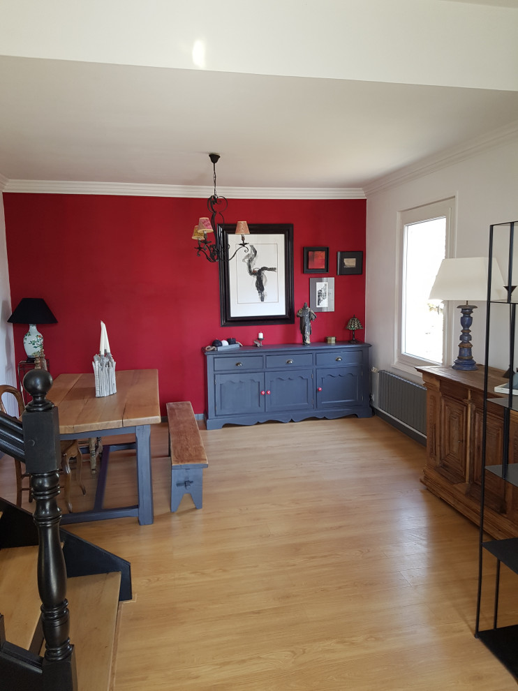 Réalisation d'une salle à manger ouverte sur le salon bohème de taille moyenne avec un mur rouge, sol en stratifié, aucune cheminée et un sol beige.