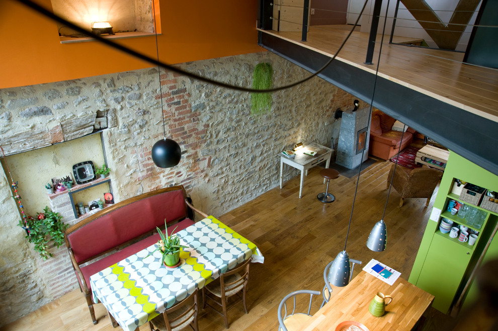 Пример оригинального дизайна: гостиная-столовая среднего размера в стиле фьюжн с оранжевыми стенами и светлым паркетным полом без камина