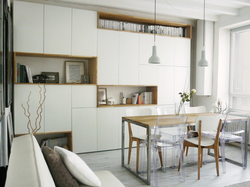 Immagine di una sala da pranzo aperta verso il soggiorno scandinava di medie dimensioni con pareti bianche, parquet chiaro e nessun camino
