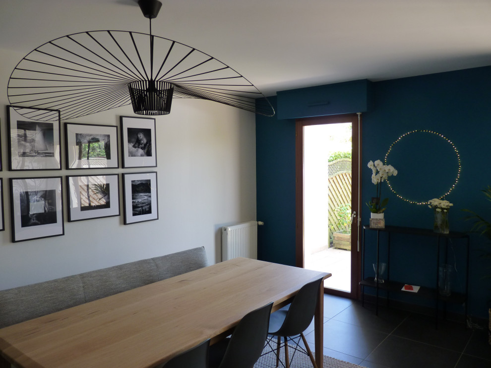 Cette photo montre une salle à manger ouverte sur le salon tendance de taille moyenne avec un mur bleu, un sol en carrelage de céramique, aucune cheminée et un sol noir.