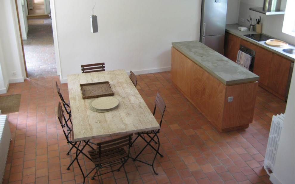 Imagen de comedor actual abierto con paredes blancas y suelo de baldosas de terracota
