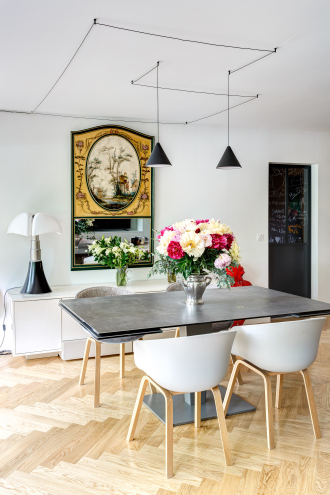Cette image montre une salle à manger design avec un mur blanc, parquet clair et un sol beige.