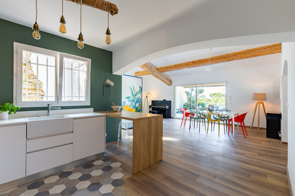 Immagine di una grande sala da pranzo aperta verso la cucina con pareti verdi, pavimento con piastrelle in ceramica e carta da parati