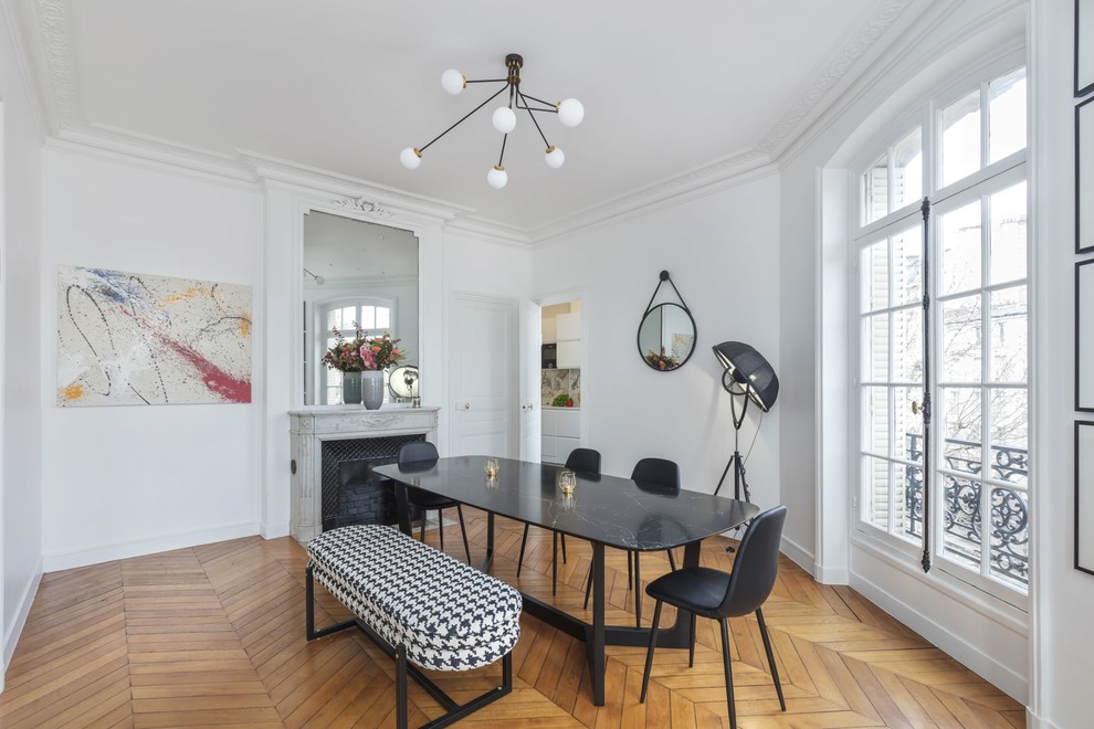Geschlossenes Modernes Esszimmer mit weißer Wandfarbe, braunem Holzboden, Kamin und gefliester Kaminumrandung in Paris