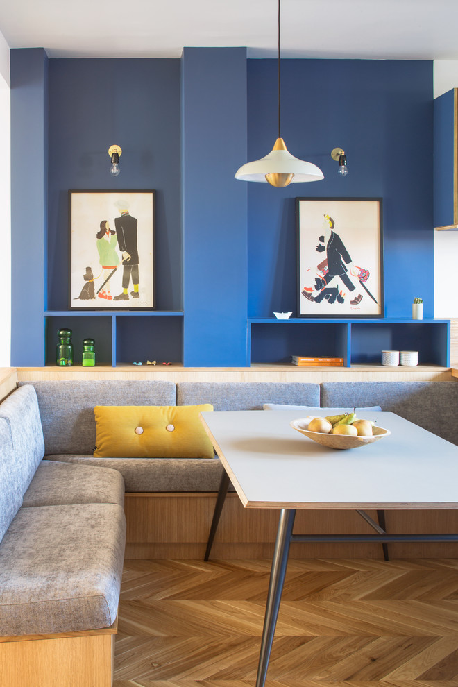 Cette image montre une salle à manger ouverte sur le salon design de taille moyenne avec un mur bleu, parquet clair et un sol beige.