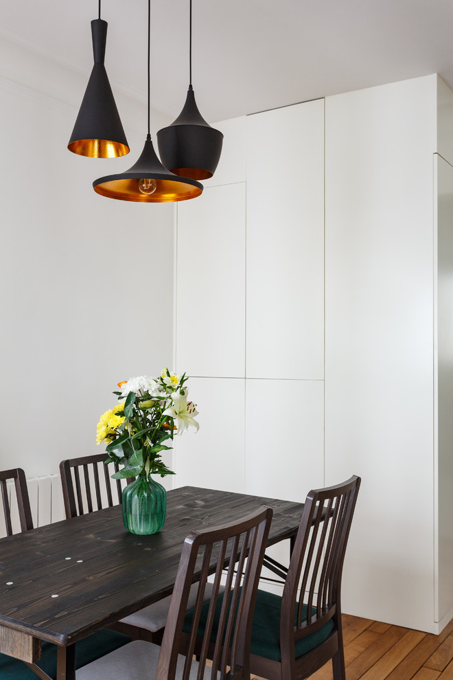 Idées déco pour une salle à manger ouverte sur le salon moderne de taille moyenne avec un mur blanc, un sol en bois brun, une cheminée standard, un manteau de cheminée en pierre et un sol marron.