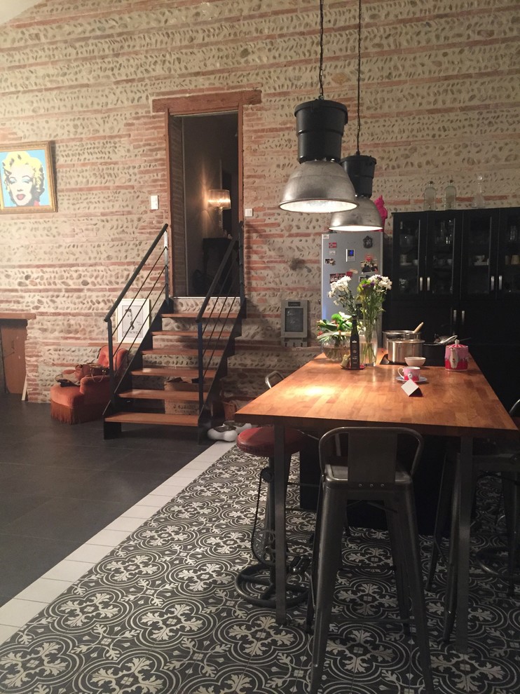 Immagine di un'ampia sala da pranzo aperta verso il soggiorno industriale con pavimento con piastrelle in ceramica e pavimento nero