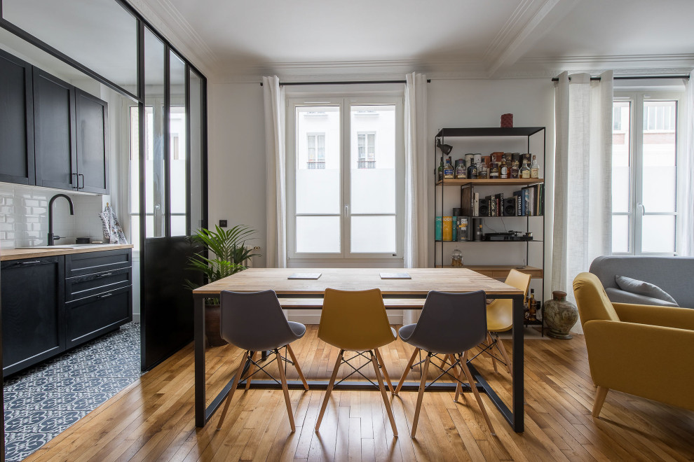 This is an example of a contemporary open plan dining room in Paris with white walls, light hardwood flooring, no fireplace and beige floors.