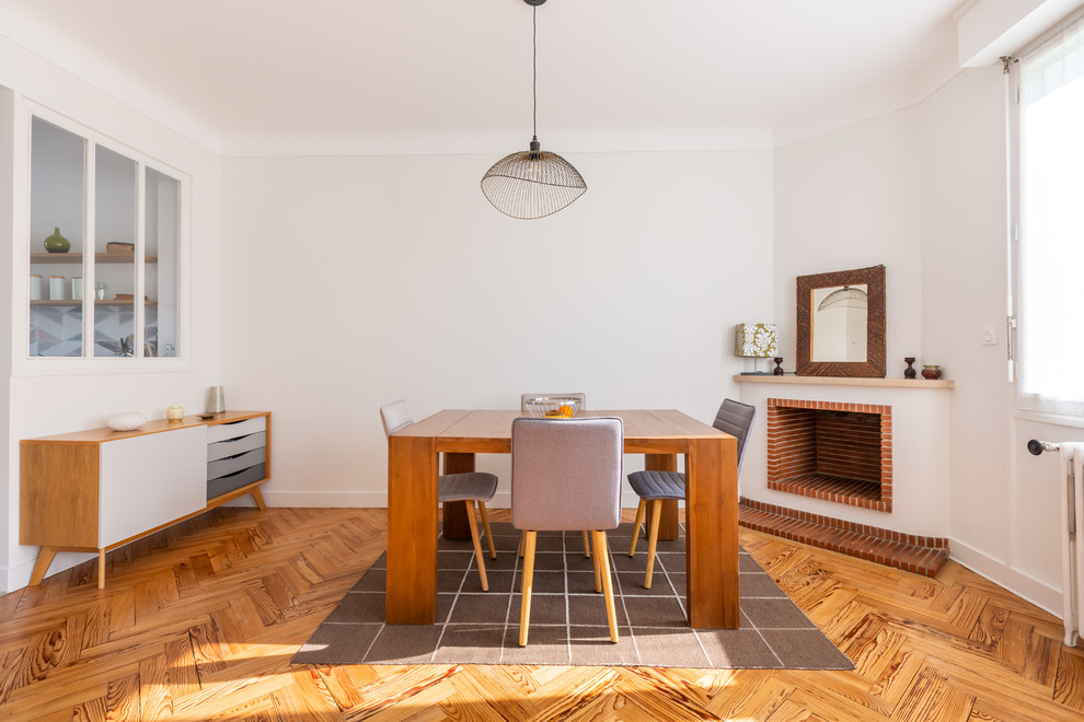 Esempio di una sala da pranzo scandinava con camino ad angolo, pareti bianche, pavimento in legno massello medio e pavimento marrone