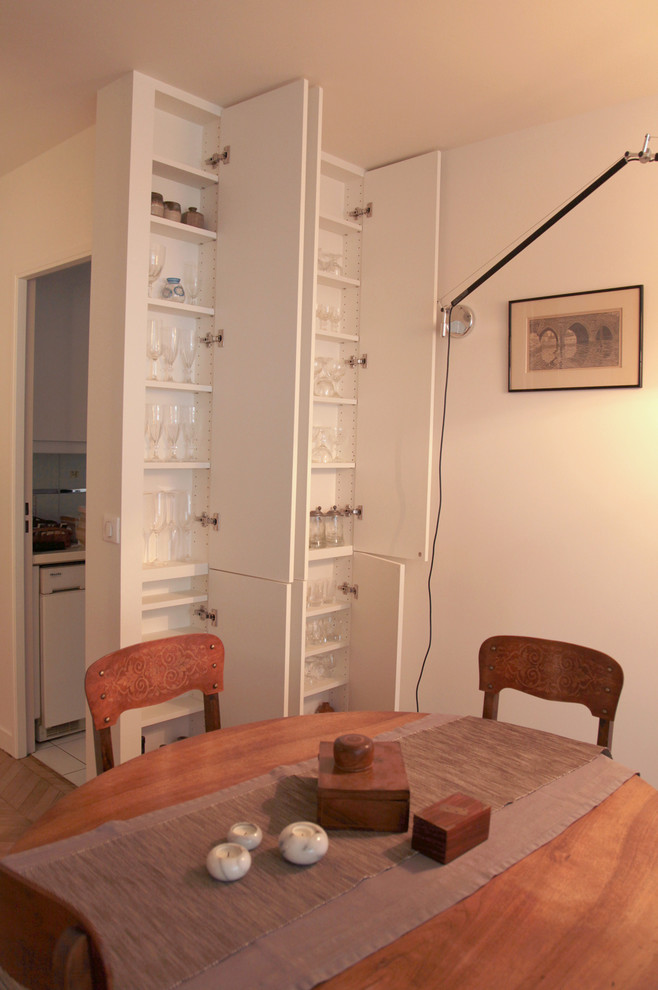 Exemple d'une salle à manger ouverte sur le salon tendance de taille moyenne avec un mur blanc et parquet clair.