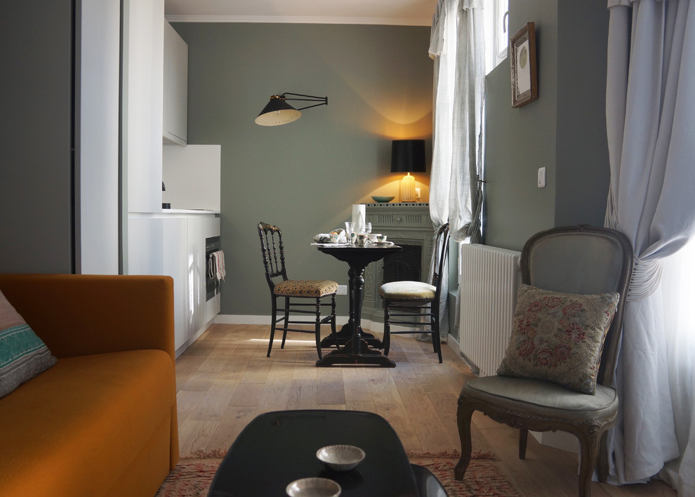 Offenes, Kleines Klassisches Esszimmer mit grüner Wandfarbe, hellem Holzboden, Kaminofen und braunem Boden in Paris
