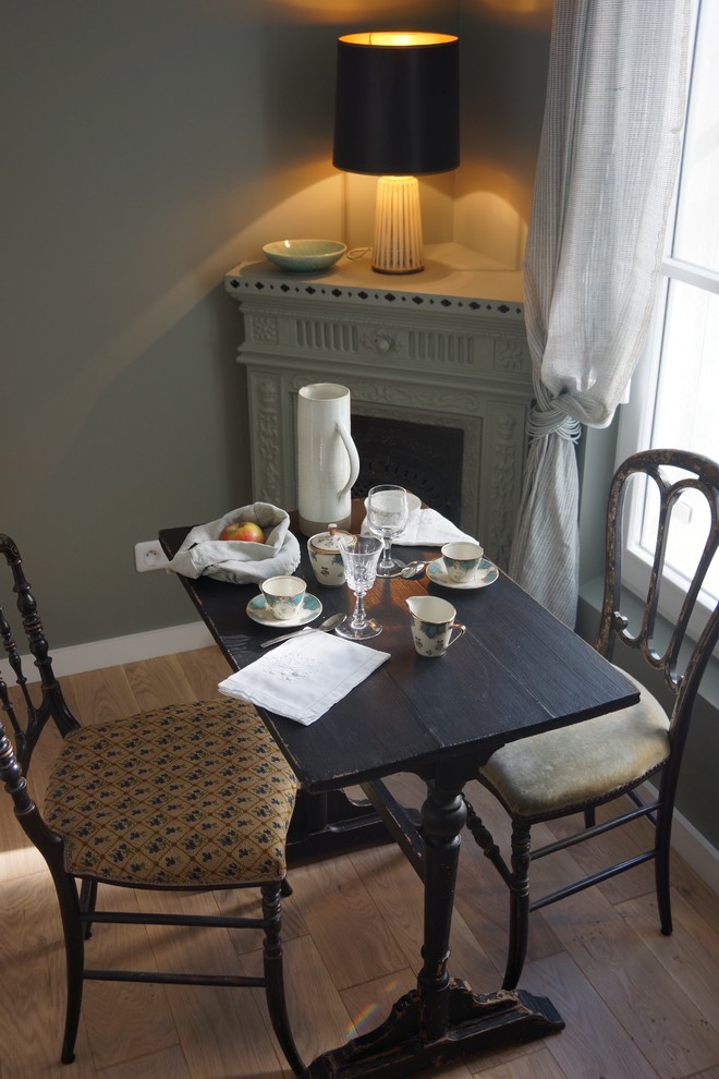 Idee per una piccola sala da pranzo aperta verso il soggiorno classica con pareti verdi, stufa a legna, parquet chiaro e pavimento marrone