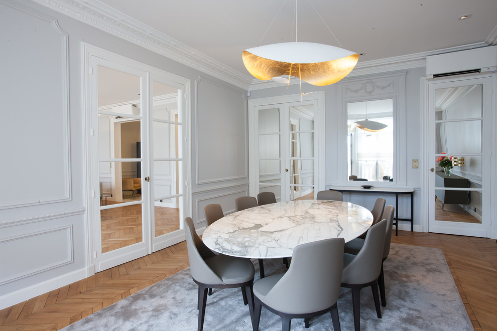 Geschlossenes, Großes Klassisches Esszimmer ohne Kamin mit grauer Wandfarbe und braunem Holzboden in Paris