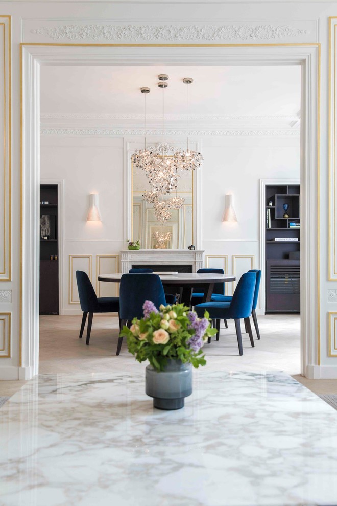 Cette image montre une grande salle à manger ouverte sur le salon traditionnelle avec un mur blanc, parquet clair, une cheminée standard et un manteau de cheminée en pierre.