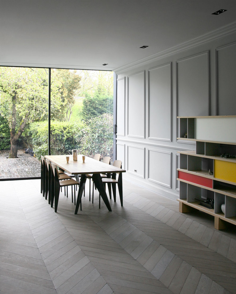 Imagen de comedor contemporáneo grande sin chimenea con paredes grises y suelo de madera clara