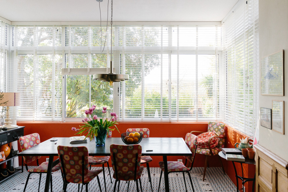 Immagine di una sala da pranzo aperta verso il soggiorno eclettica di medie dimensioni con pareti arancioni, pavimento in terracotta e pavimento blu