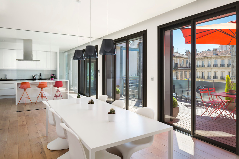 Cette photo montre une très grande salle à manger ouverte sur le salon tendance avec un mur blanc et parquet clair.