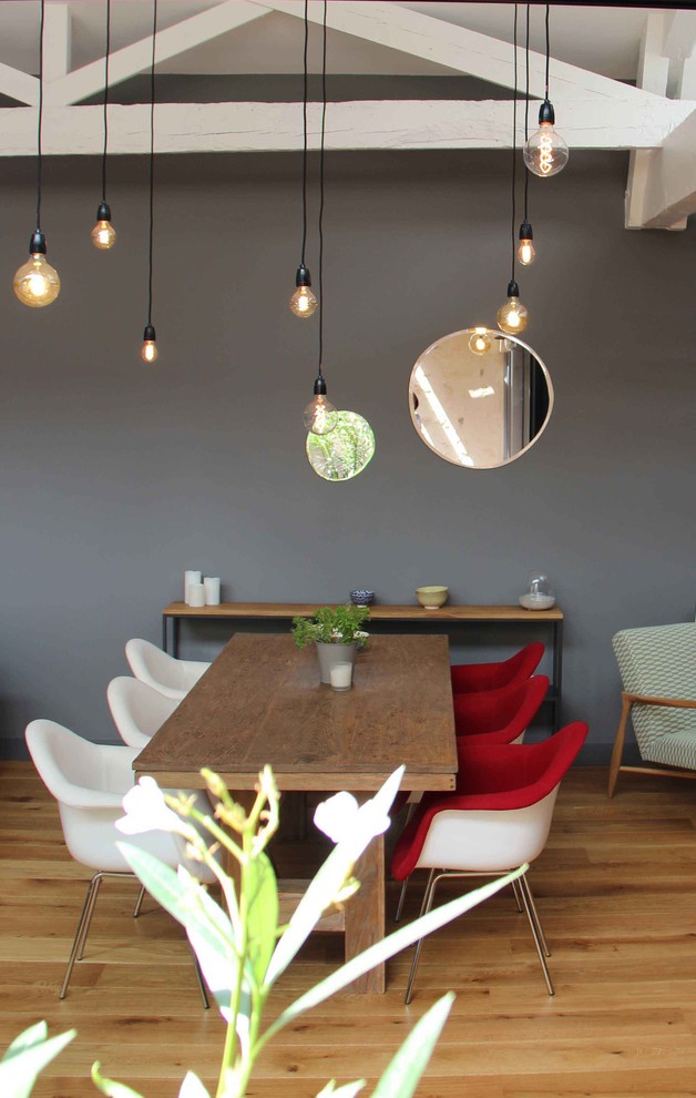 Imagen de comedor actual con paredes grises y suelo de madera clara