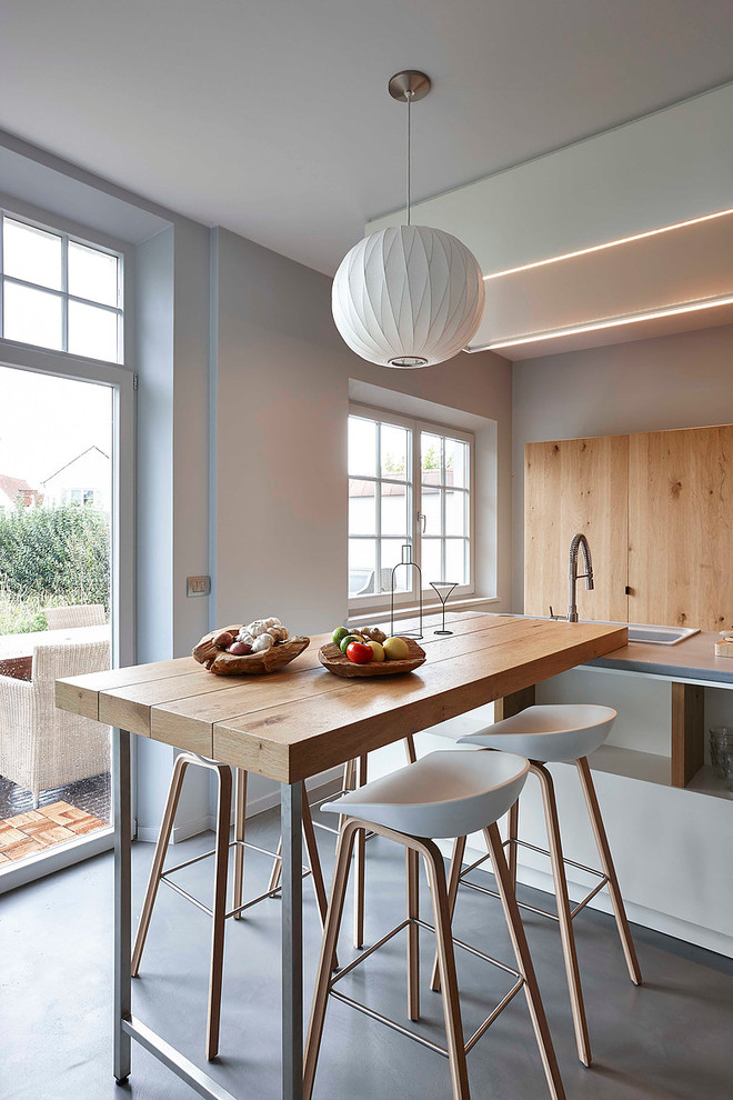 Esempio di una piccola sala da pranzo aperta verso la cucina design con pareti bianche e pavimento in cemento