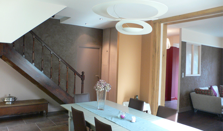 Idée de décoration pour une salle à manger ouverte sur le salon minimaliste de taille moyenne avec un mur marron, un sol en carrelage de céramique, cheminée suspendue, un manteau de cheminée en métal et un sol marron.