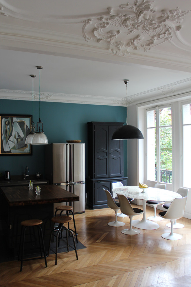 Foto di una grande sala da pranzo aperta verso la cucina contemporanea con pareti blu, parquet chiaro e nessun camino